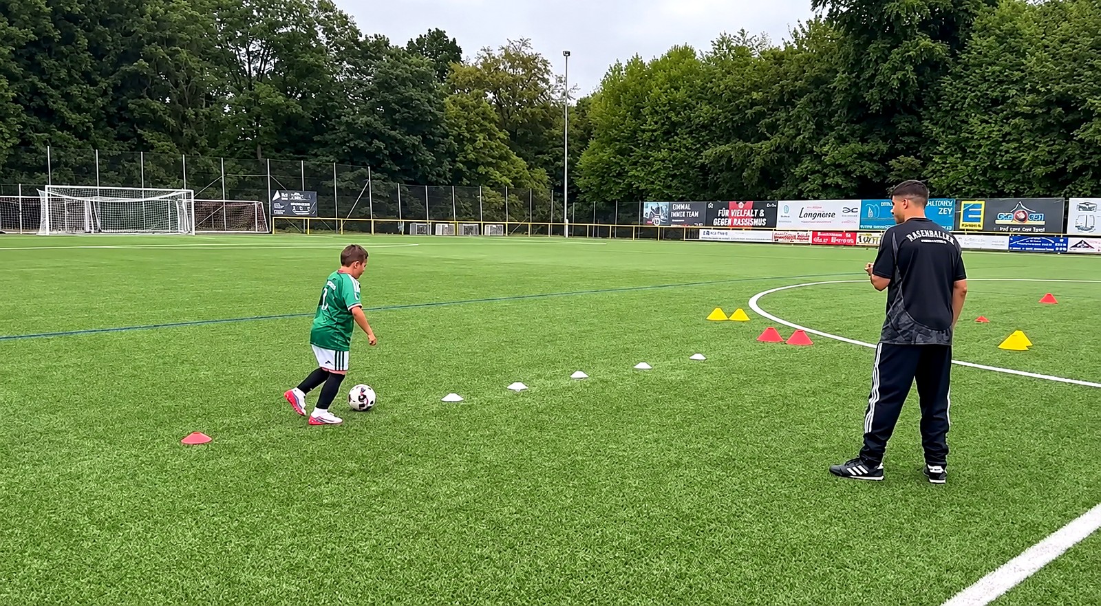Einzeltraining der Rasenhelden Fußballschule Wiesbaden — Trainer betreut ein Kind beim Dribbling durch den Hütchen-Parcours