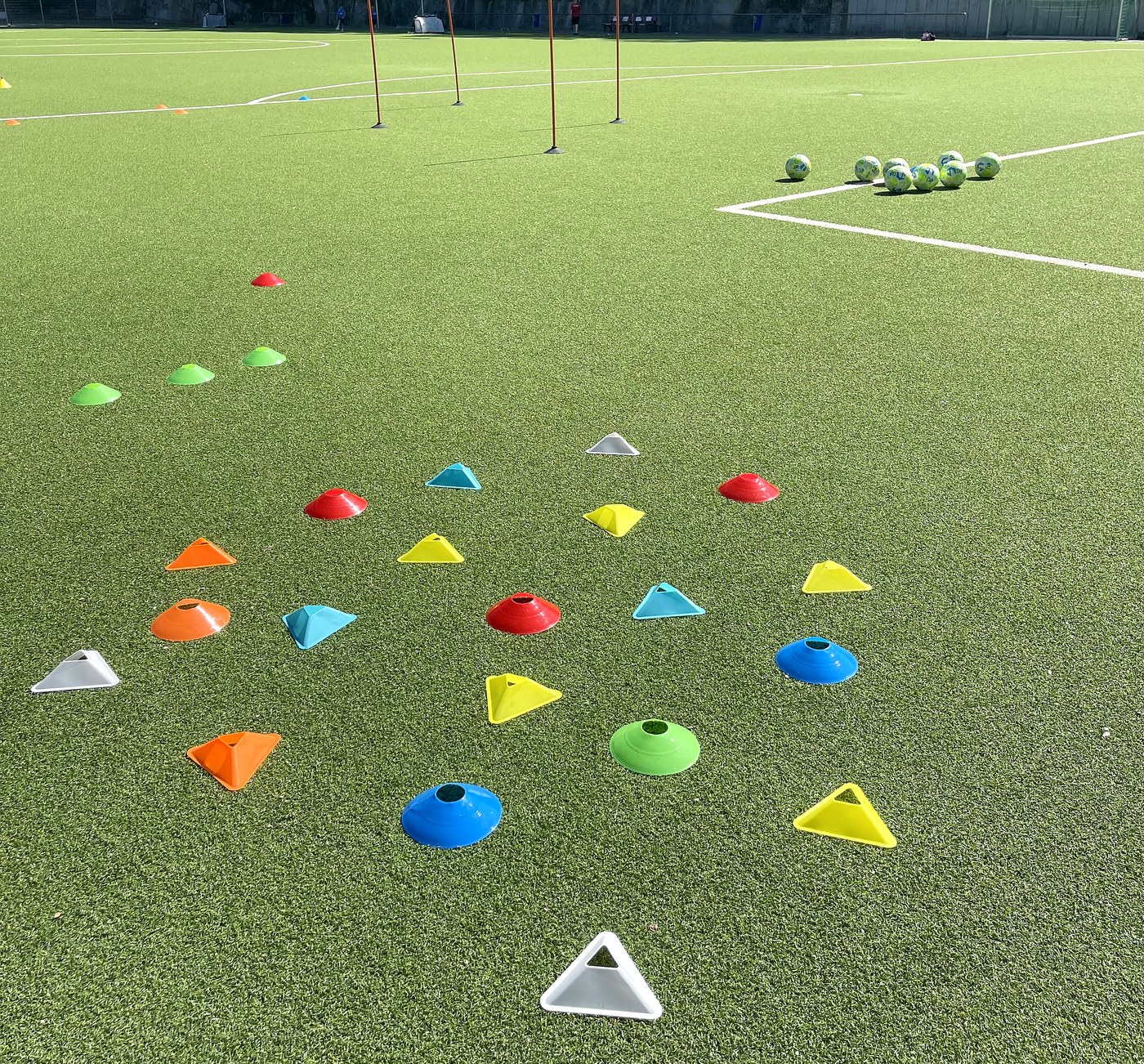 Bunter Trainingsaufbau der Rasenhelden Fußballschule in Wiesbaden mit Hütchen, Stangen und Bällen auf dem Kunstrasen